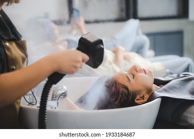 Hairdresser in beauty salon hair care in procedure of steaming water steam. Service steaming ozone in spa and salon shop, Woman having her hair washed in a hairdressing salon, massage head customer