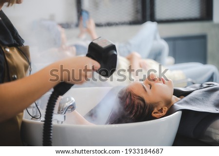 Hairdresser in beauty salon hair care in procedure of steaming water steam. Service steaming ozone in spa and salon shop, Woman having her hair washed in a hairdressing salon, massage head customer