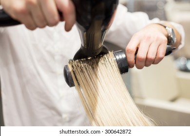 Hairdresser Blow Drying Blonde Woman's Hair