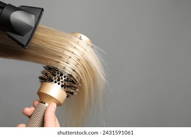 Hairdresser blow drying client's hair on light grey background, closeup. Space for text - Powered by Shutterstock