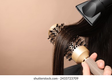 Hairdresser blow drying client's hair on beige background, closeup. Space for text - Powered by Shutterstock