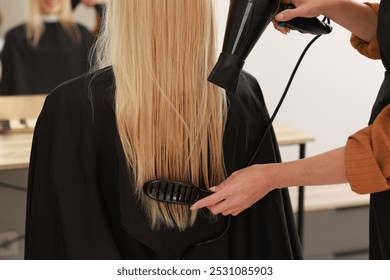 Hairdresser blow drying client's hair in salon, closeup - Powered by Shutterstock