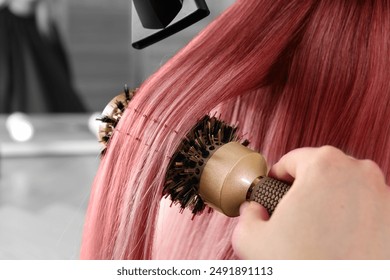 Hairdresser blow drying client's pink hair in salon, closeup - Powered by Shutterstock