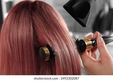 Hairdresser blow drying client's pink hair in salon, closeup - Powered by Shutterstock