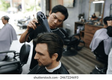 Hairdresser blow drying freshly cut hair of client - Powered by Shutterstock