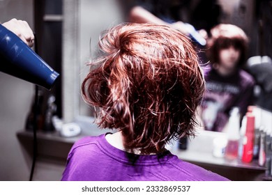 hairdresser blow-dries with red hair after a haircut in a teenage girl. Everyday life and fashion trends - Powered by Shutterstock