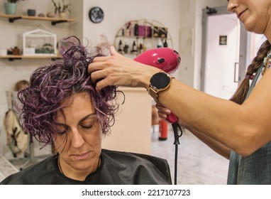 Hairdresser Blow-Drying And Curling Client's Hair In Salon.
Woman At The Hairdresser. Female Hairdresser While Working.
 Mature Woman Having Her Hair Done In A Beauty Salon. 