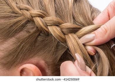 Hairdresser braids long straight hair isolated on white background.
