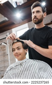 Hairdresser Combing Hair Of Teen Client In Beauty Salon