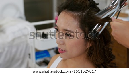 Hairdresser creating a hairstyle for female model in salon