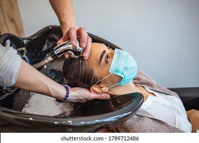 Hairdresser and customer in a salon with medical masks during virus pandemic. Working with safety mask. Hair dresser washing the hair of a client during coronavirus quarantine - Shutterstock ID 1789712486