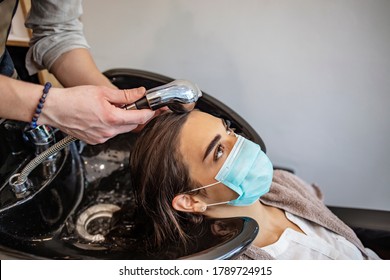 Hairdresser and customer in a salon with medical masks during virus pandemic. Working with safety mask. Hair dresser washing the hair of a client during coronavirus quarantine - Shutterstock ID 1789724915