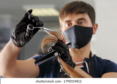 A Hairdresser Cuts The Long Hair Of A Young Girl. A Barber In Black Nitrile Gloves And A Reusable Mask Uses Scissors And A Comb.