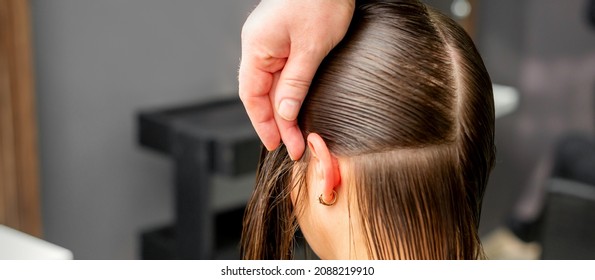 Hairdresser divides female hair into sections with comb holding hair with her hands in hair salon close up - Shutterstock ID 2088219910