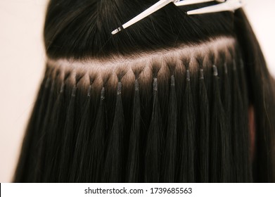 The hairdresser does hair extensions to a young girl in a beauty salon. Professional hair care. Close up of capsules and strands of grown hair - Shutterstock ID 1739685563