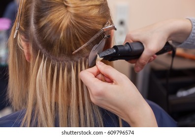 The hairdresser does hair extensions to a young girl, a blonde in a beauty salon. Professional hair care. - Shutterstock ID 609796574
