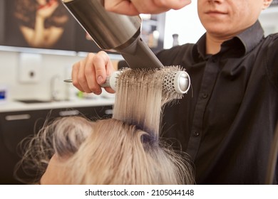 Hairdresser doing blowout hairstyle for client in beauty salon - Shutterstock ID 2105044148