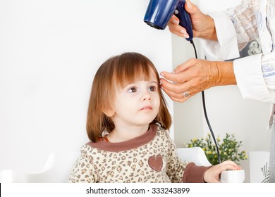 Hairdresser  dries hair of cute little girl