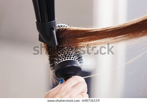 Hairdresser\
dries hair with a hairdryer in beauty\
salon