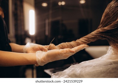 The hairdresser dyeing blonde hair roots with a brush for a young woman in a hair salon. High quality photo - Powered by Shutterstock