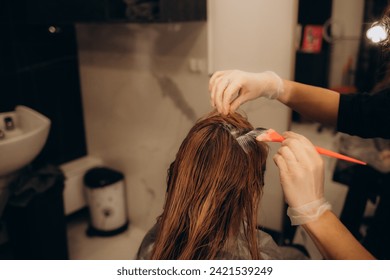 The hairdresser dyeing blonde hair roots with a brush for a young woman in a hair salon. High quality photo - Powered by Shutterstock