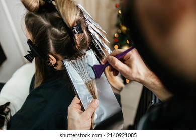 Hairdresser is dyeing female hair, making hair highlights to his client with a foil.  - Powered by Shutterstock