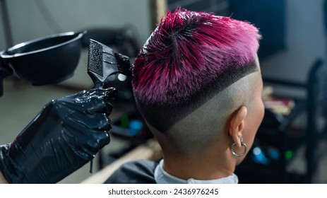 The hairdresser dyes the hair of an Asian woman in pink. Short extreme haircut.  - Powered by Shutterstock