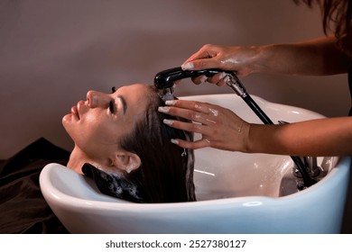 Hairdresser hands washing lady head in spa salon for create hairstyle. Hairstylist wash woman hair with shampoo in barber shop. Concept of customer service at hair salon, haircare. Copy ad text space - Powered by Shutterstock