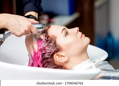 Hairdresser hands washing pink dyed hair of woman in sink, close up. - Powered by Shutterstock