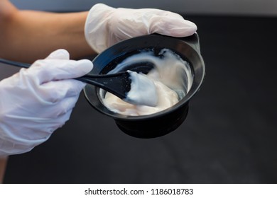 hairdresser holds a bowl of hair dye on a black background - Powered by Shutterstock