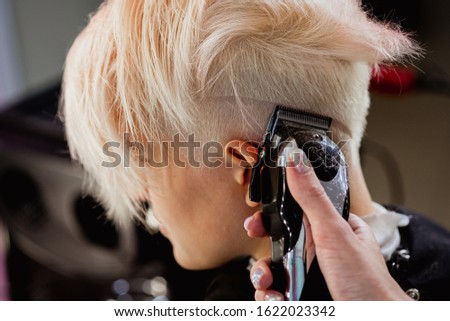 Similar – Image, Stock Photo Barber shaves the temple with cordless trimmer during a short haircut on the sides of the head.