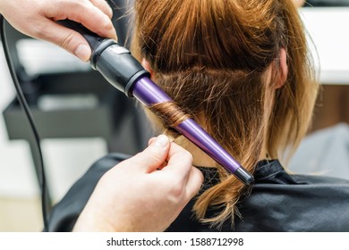 Hairdresser Make Hair Wavy For Woman With Electric Hair Curler, Closeup.