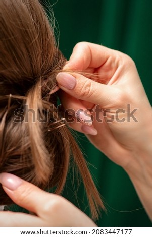Hairdresser makes hairstyles for a young woman in beauty salon close up
