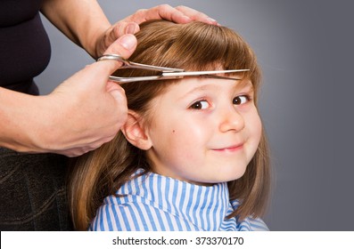 Hairdresser making a hair style to cute little girl