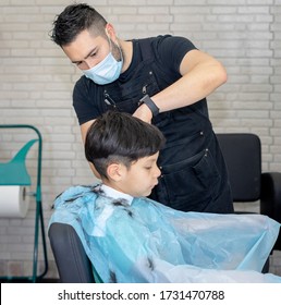 Hairdresser with a mask in his mouth cuts the hair of a child in the hairdresser while maintaining security measures for the pandemic.