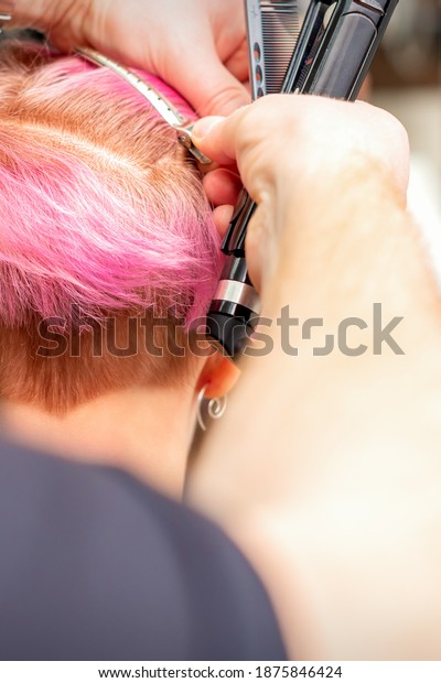Hairdresser pinches hair with the clip before doing\
hairstyle in a hair\
salon