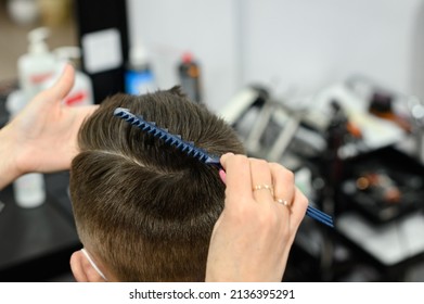 Hairdresser puts hair to teen boy after haircut, haircut for teen, styling after haircut with gel and comb. - Shutterstock ID 2136395291