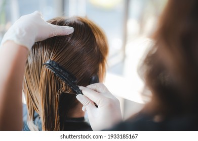 Hairdresser putting mask and coloring on woman's hair in beauty salon, Professional hairdresser dyeing hair of her client, Process of dyeing hair at beauty salon - Powered by Shutterstock