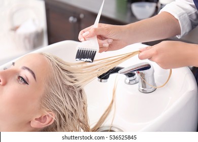 Hairdresser Putting Mask On Woman's Hair In Salon