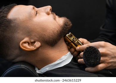 Hairdresser shaves hair on client neck creating beard shape with machine in barbershop closeup. Barber uses electrical shaver in salon - Powered by Shutterstock