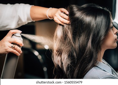 Hairdresser spraying woman’s long black hair with hair spray. - Powered by Shutterstock