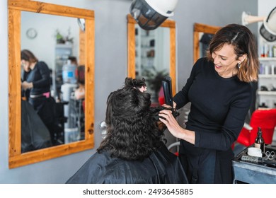 A hairdresser straightens a client's curly hair in a salon. The scene is captured from the back, showing the hairdresser's careful technique. - Powered by Shutterstock