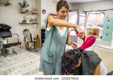 Hairdresser Styling A Client. Hairdresser At Her Work Station Styling And Drying The Hair Of A Mature Woman In The Beauty Salon.