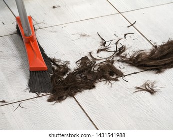 Hairdresser Sweeping Hair Clippings On Floor In Barber Shop. 