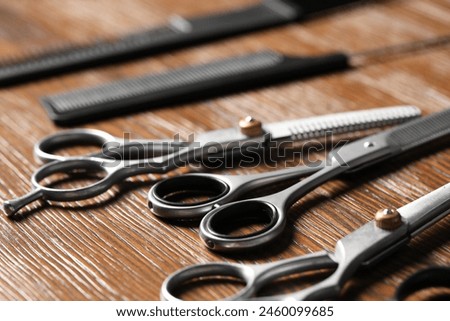 Hairdresser tools. Different scissors and combs on wooden table, closeup