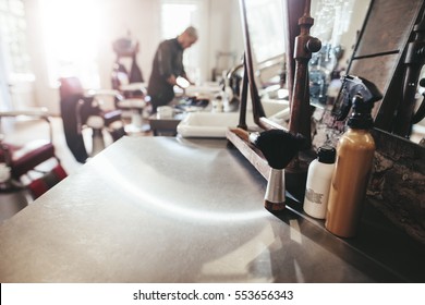 Hairdresser tools on counter with barber in background. Barber shop with hairstyling equipments, - Powered by Shutterstock