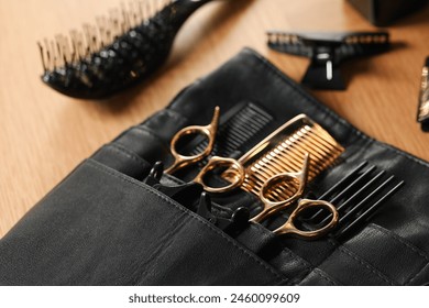 Hairdresser tools. Professional scissors and combs in leather organizer on wooden table, closeup - Powered by Shutterstock