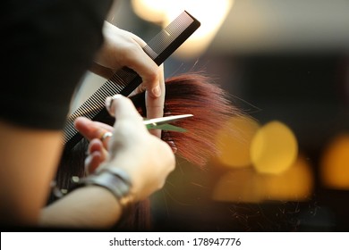 Hairdresser trimming brown hair with scissors - Shutterstock ID 178947776