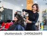 A hairdresser uses a curling iron to curl a client