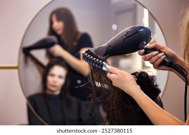 Hairdresser using black hair dryer and comb in salon for hairstyle adult woman, mirror reflection. Hairstylist dried head in barber shop. Customer service at hair salon, haircare. Copy ad text space - Powered by Shutterstock